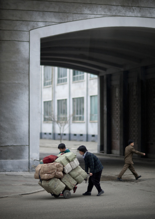 North Korean mother and child pushing a heavy trolley in the city, Pyongan Province, Pyongyang, North Korea