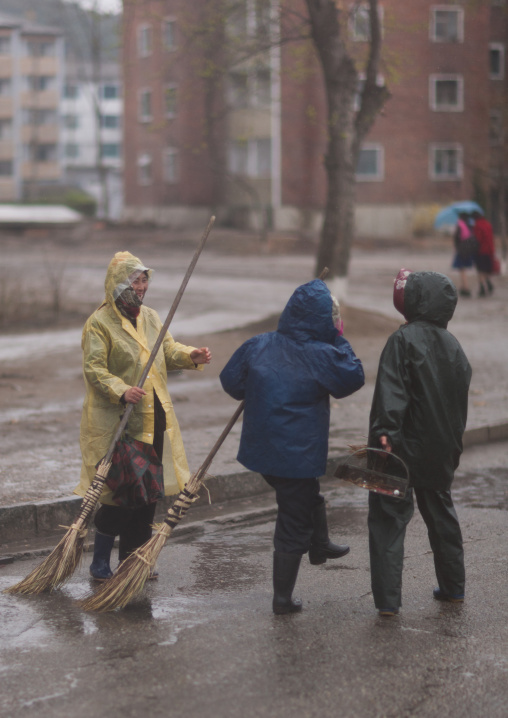 North Korean people cleaning the road with brooms under the rain, Pyongan Province, Pyongyang, North Korea