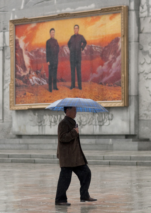 North Korean man with an umbrella in front of a fresco with the Dear Leaders posing on mount Paektu, Pyongan Province, Pyongyang, North Korea