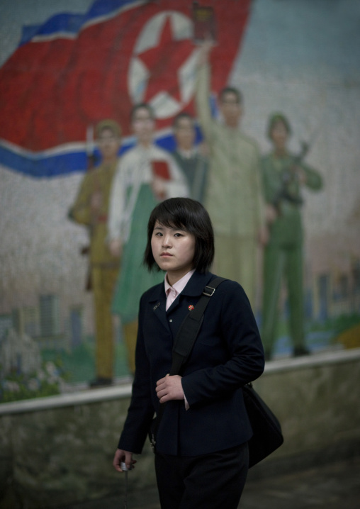 North Korean young woman in the subway in front of a propaganda mosaic, Pyongan Province, Pyongyang, North Korea