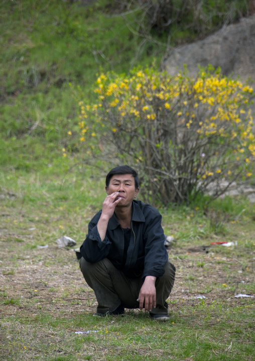 North Korean man squatting in a park, North Hwanghae Province, Kaesong, North Korea