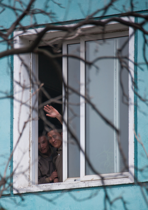 North Korean men waving from a window, Pyongan Province, Pyongyang, North Korea