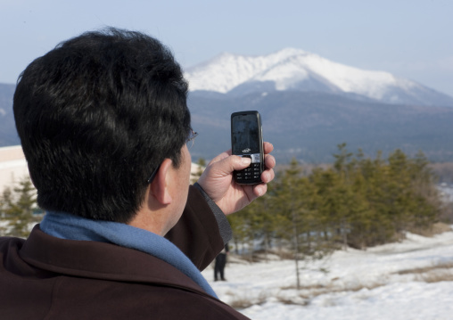 North Korean man taking picture of mount Paektu with his mobile phone, Ryanggang Province, Samjiyon, North Korea