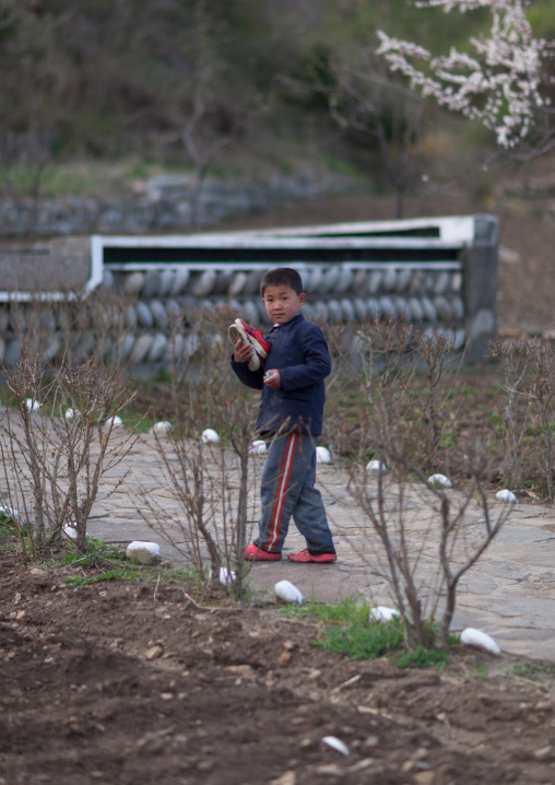Portrait of North Korean boy in a village with shoes in his hands, North Hamgyong Province, Jung Pyong Ri, North Korea