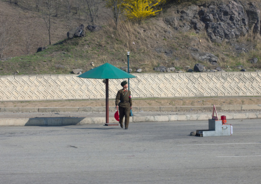 Soldier under umbrella at a checkpoint on a highway, Pyongan Province, Pyongyang, North Korea