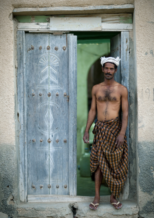Indian Worker Standing Beside A Blue Wooden Door, Salalah, Oman