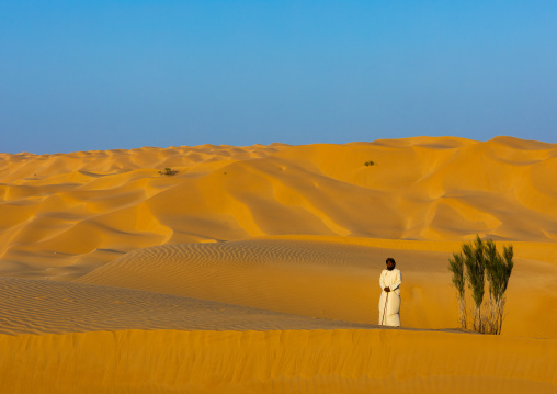 Omani man standing near a tree in the rub al khali desert, Dhofar Governorate, Rub al Khali, Oman