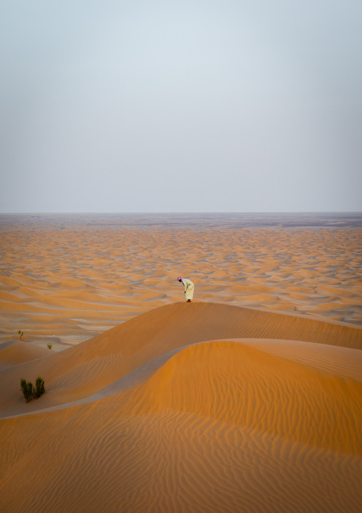 Omani man praying at the top of a dune in rub al khali desert, Dhofar Governorate, Rub al Khali, Oman