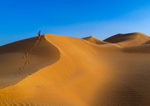 Tourist woman climbing a dune in the rub al khali desert, Dhofar Governorate, Rub al Khali, Oman