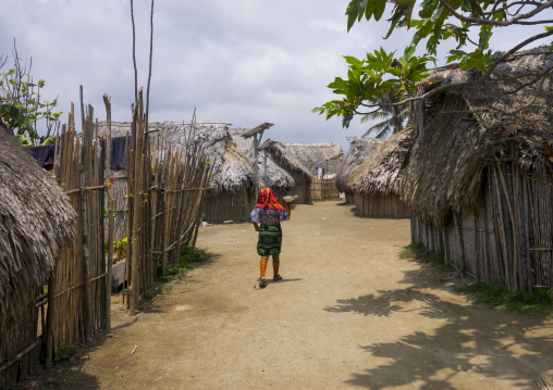 Panama, San Blas Islands, Mamitupu, Kuna Woman Passing In Front Traditional Houses With A Solar Panel