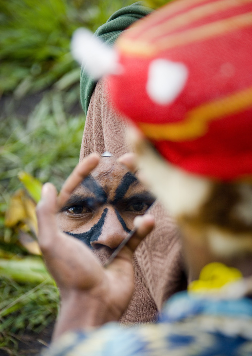 Warrior looking at himself in a mirror before a Sing-sing, Western Highlands Province, Mount Hagen, Papua New Guinea