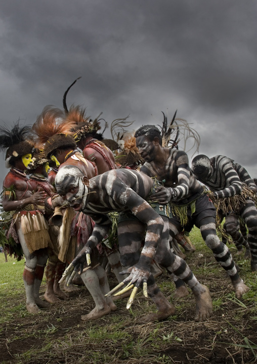 Snake men with hulis warriors during a sing-sing under a storm, Western Highlands Province, Mount Hagen, Papua New Guinea