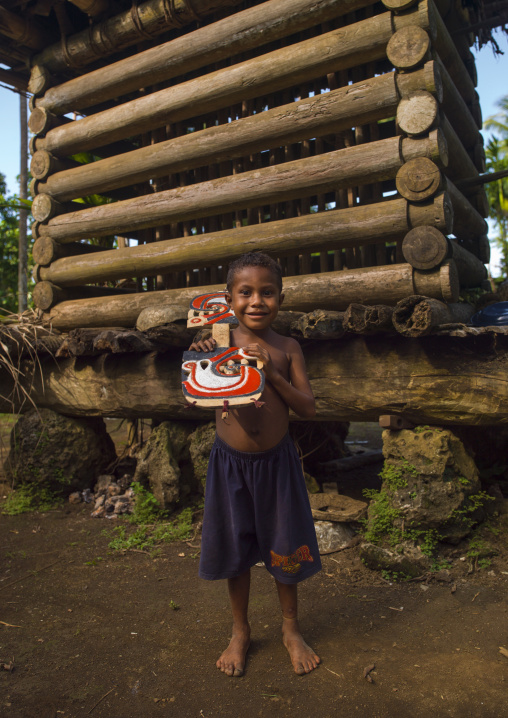 Boy with a malagan in front of a yam house, Milne Bay Province, Trobriand Island, Papua New Guinea