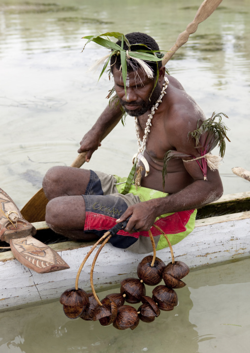 Man on a pirogue making a shark calling with coconut rattle, New Ireland Province, Kavieng, Papua New Guinea
