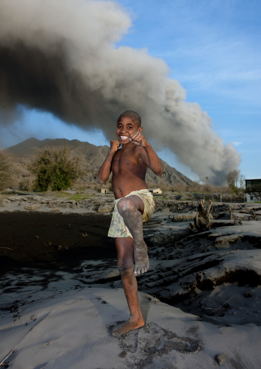 Boy doing karate under a volcanic eruption in tavurvur volcano, East New Britain Province, Rabaul, Papua New Guinea