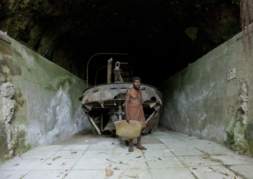 Man inside karavia tunnel in front of a boat wreck, East New Britain Province, Rabaul, Papua New Guinea