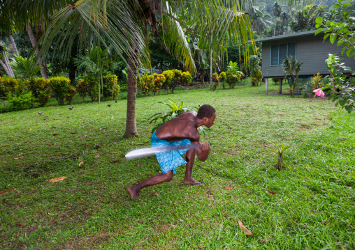 Man cutting grass in a garden with a machette, East New Britain Province, Rabaul, Papua New Guinea