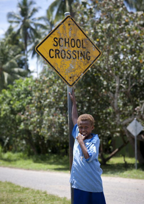 Boy standing in front of a road sign for a school, East New Britain Province, Rabaul, Papua New Guinea