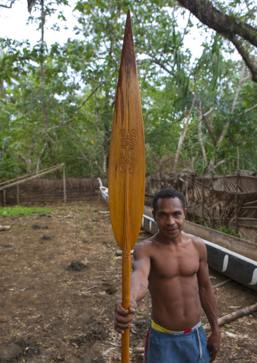 Man showing a long wooden boat paddle, Milne Bay Province, Alotau, Papua New Guinea