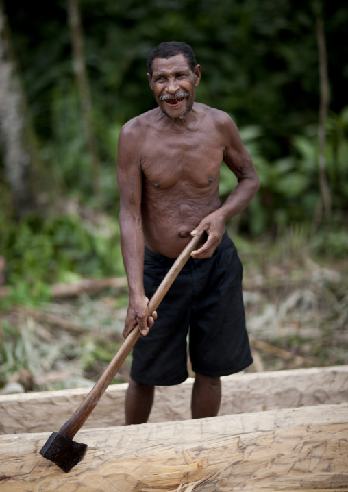 Man carving a canoe in the forest, Milne Bay Province, Alotau, Papua New Guinea