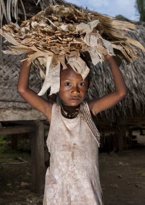 Girl holding dried banana leaves used as traditional money, Milne Bay Province, Trobriand Island, Papua New Guinea