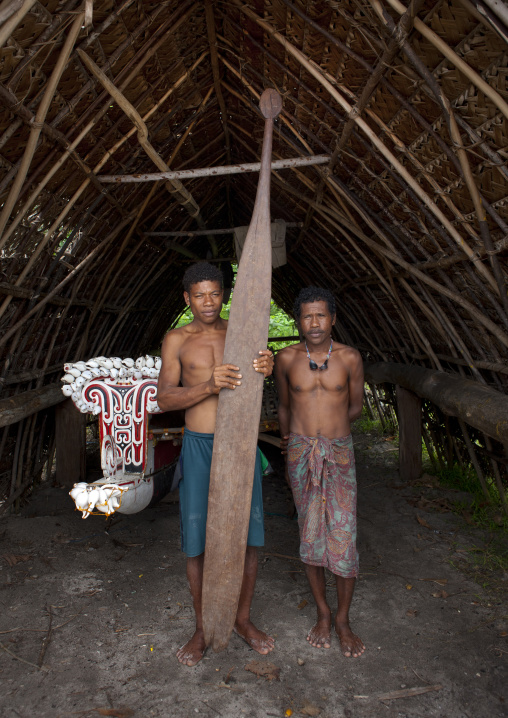 Men with a big boat paddle in front of a traditional canoe, Milne Bay Province, Trobriand Island, Papua New Guinea