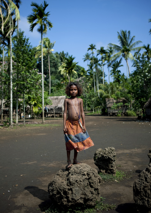 Girl standing on the former yam house stones, Milne Bay Province, Trobriand Island, Papua New Guinea