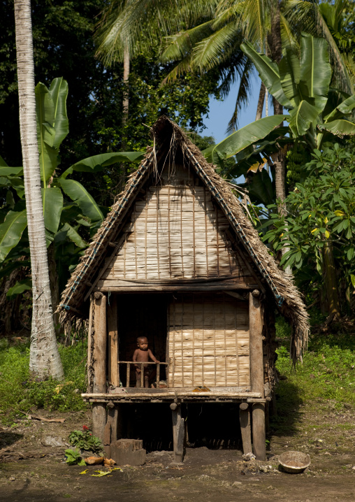 Child standing at the entrace of a traditional house, Milne Bay Province, Trobriand Island, Papua New Guinea