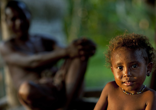 Portrait of a little girl with in her father in the background, Milne Bay Province, Trobriand Island, Papua New Guinea