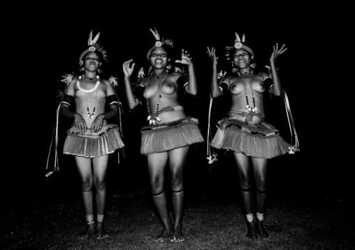 Portrait of topless tribal women in traditional clothing dancing at night, Milne Bay Province, Trobriand Island, Papua New Guinea