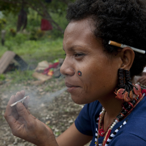 Woman smoking cigarette, Milne Bay Province, Trobriand Island, Papua New Guinea