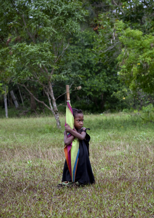 Girl with an umbrella in a field, Milne Bay Province, Trobriand Island, Papua New Guinea