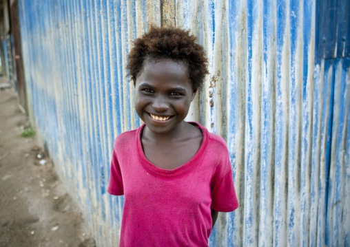 Portrait of a smiling girl in front of a blue metalic fence, Autonomous Region of Bougainville, Bougainville, Papua New Guinea