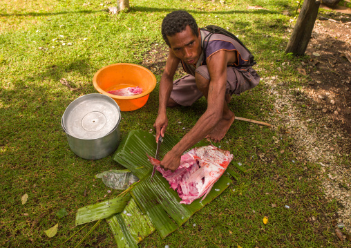 Man cutting fresh meat in a garden, Milne Bay Province, Trobriand Island, Papua New Guinea