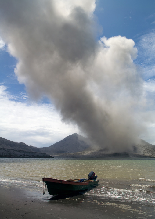 Boat in front of a volcanic eruption in Tavurvur volcano, East New Britain Province, Rabaul, Papua New Guinea