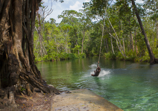 Boy jumping in a river with a rope, New Ireland Province, Laraibina, Papua New Guinea