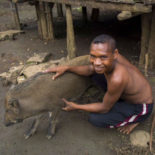 Man with a pig in front of his house, Milne Bay Province, Trobriand Island, Papua New Guinea