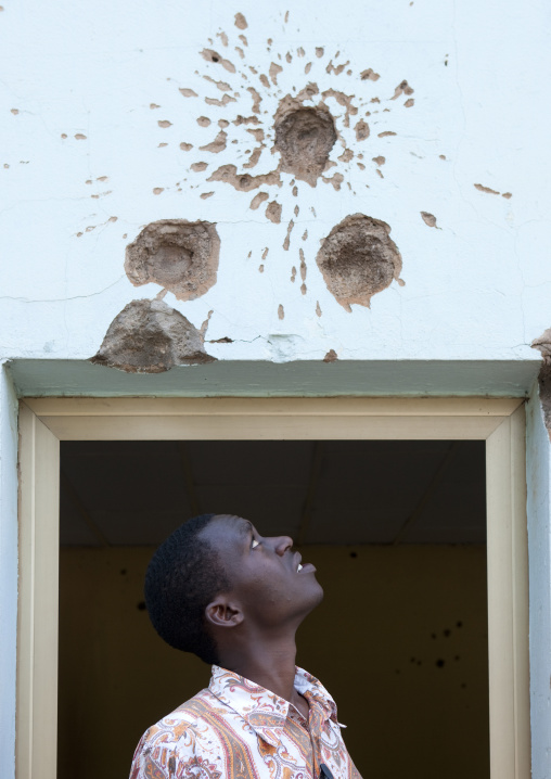 Rwandan man looking at bullets holes in camp kigali memorial site, Kigali Province, Kigali, Rwanda