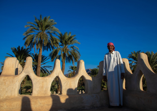 Saudi man standing on the crenelated terrace of his mud house, Najran Province, Najran, Saudi Arabia