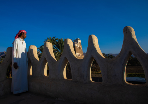 Saudi man standing on the crenelated terrace of his mud house, Najran Province, Najran, Saudi Arabia