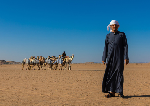 Saudi man in front of camels training for race in the Rub' al Khali desert, Najran province, Hubuna, Saudi Arabia