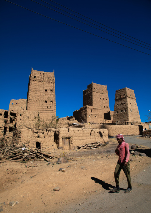Man passing in front of traditional old multi-storey mud houses, Asir province, Dahran Aljanub, Saudi Arabia
