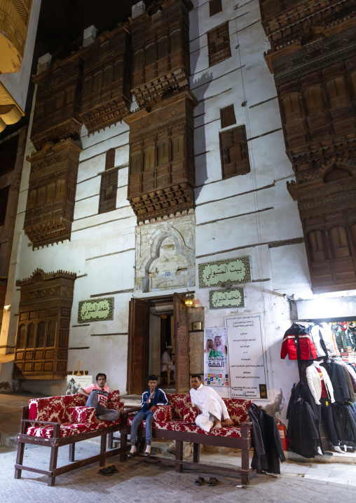 Men resting on beds in front of a historic house with wooden mashrabiyas in al-Balad, Mecca province, Jeddah, Saudi Arabia