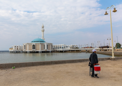 Saudi man holding a cooler in front of the floating mosque or masjid Bibi Fatima, Mecca province, Jeddah, Saudi Arabia