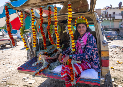 A flower vendor preparing floral garlands and crowns on a market in the back of his car, Jizan Province, Addayer, Saudi Arabia