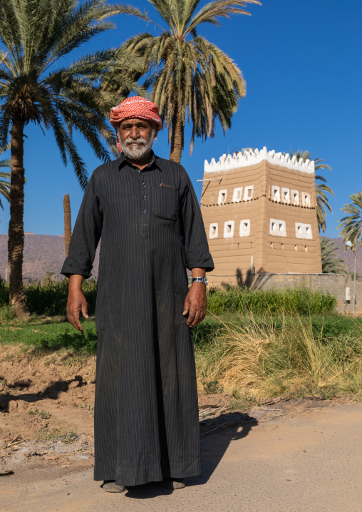 Saudi farmer standing in front of a traditional old mud house, Najran Province, Najran, Saudi Arabia