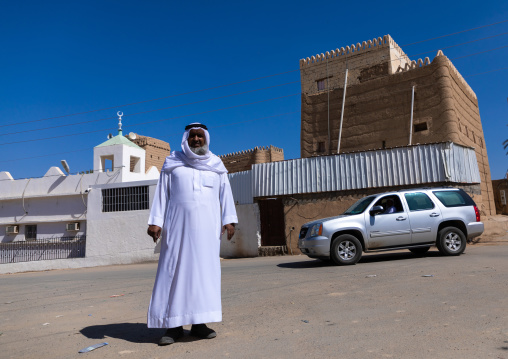 Saudi man standing in front of a traditional old mud house, Najran Province, Najran, Saudi Arabia
