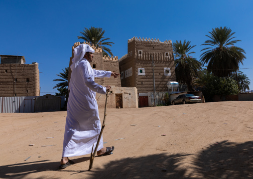 Saudi man passing in front of traditional old mud houses, Najran Province, Najran, Saudi Arabia