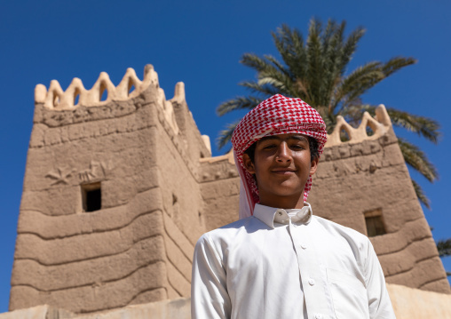 Young saudi man in front of a traditional old mud house, Najran Province, Najran, Saudi Arabia