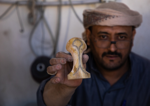 A saudi man prepares a traditional janbiya dagger for sale inside his shop, Najran Province, Najran, Saudi Arabia